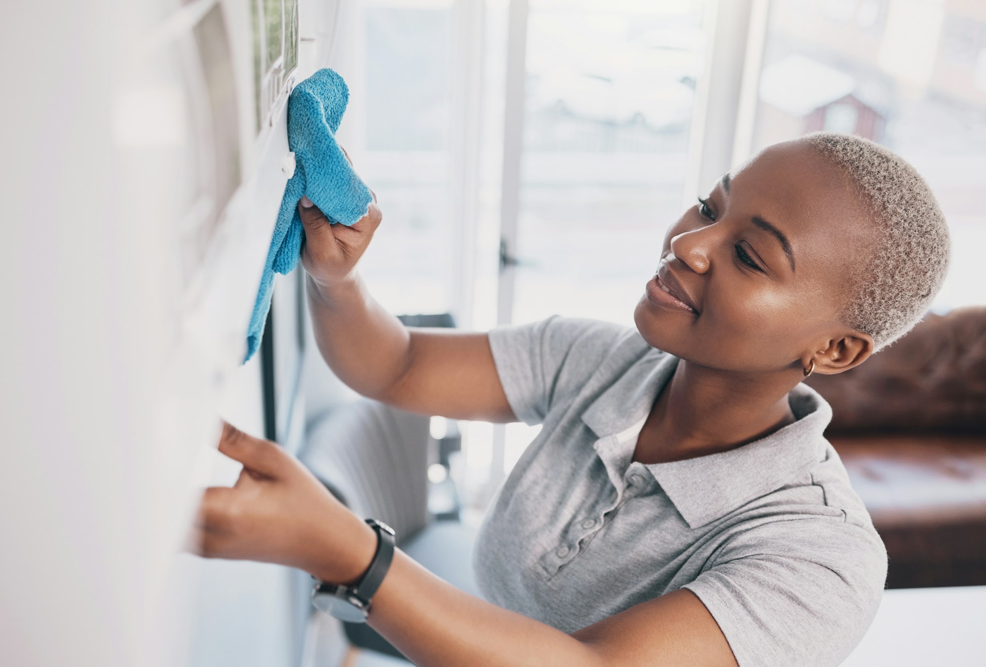 Cleaning, happy and dust with black woman in living rom for housekeeping, hygiene and disinfection.