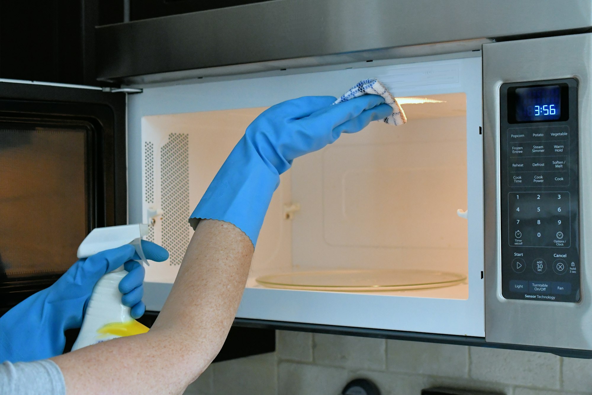 Doing housework chores by cleaning the microwave in the kitchen