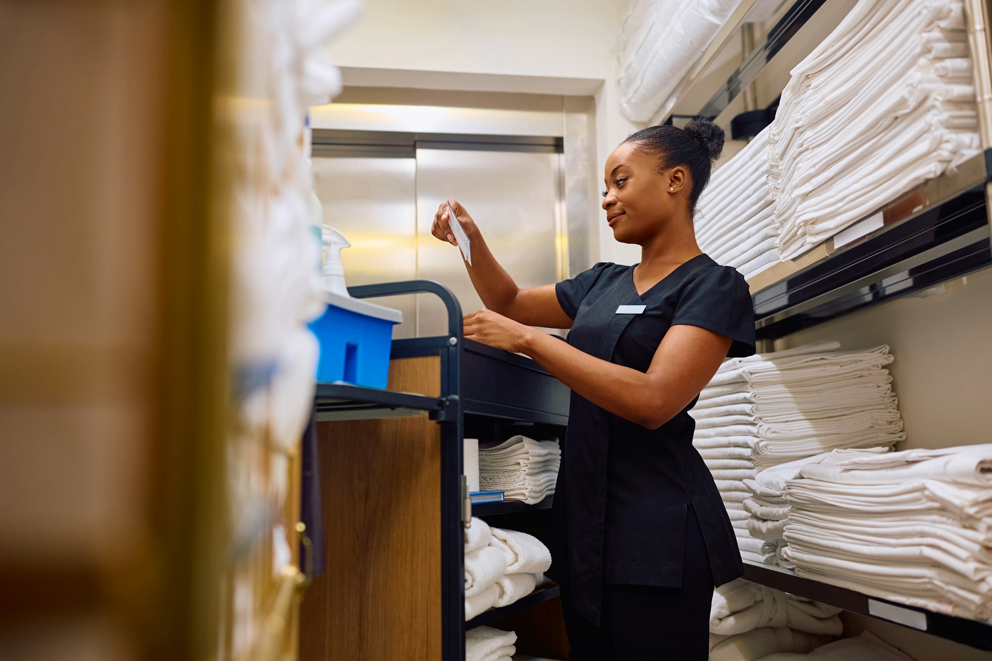 Young black chambermaid in hotel laundry room.